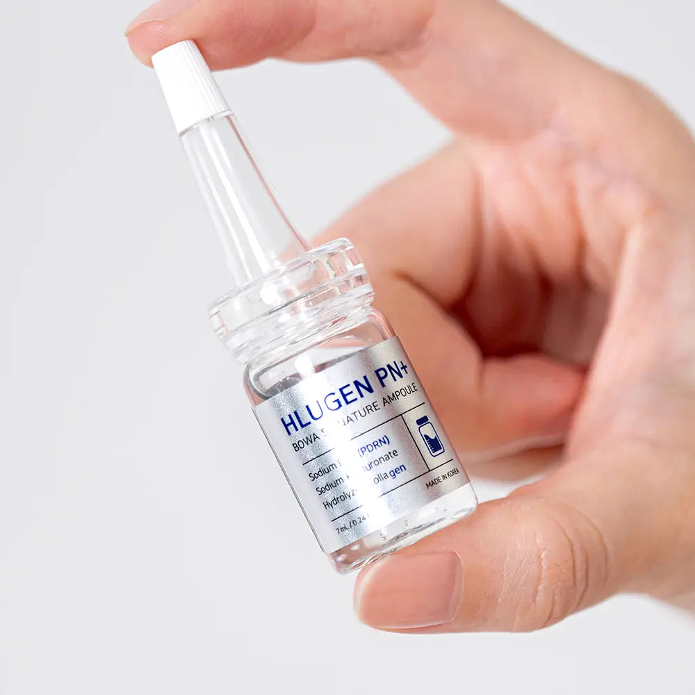 Hand holding a bottle of Hlugen PH+ solution against a light background
